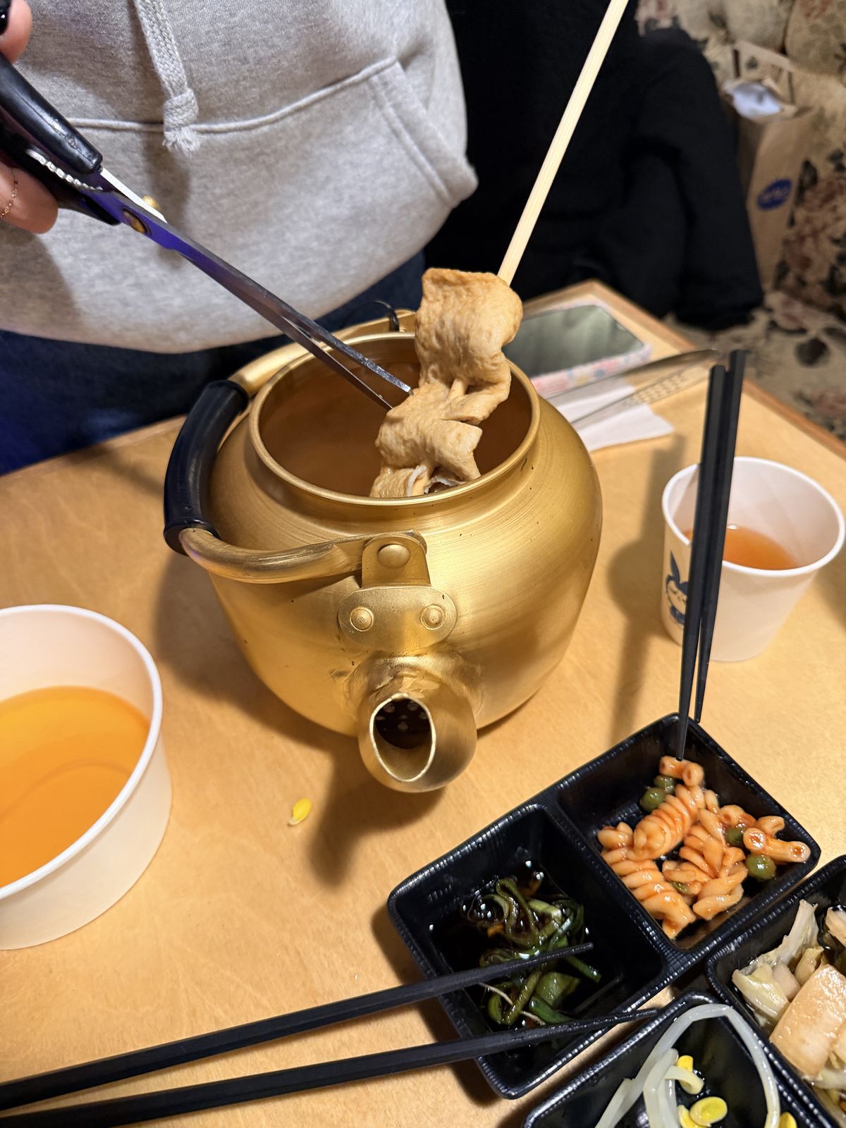 金色茶壺鍋煮著魚板串的어묵탕,旁邊是自助吧小菜