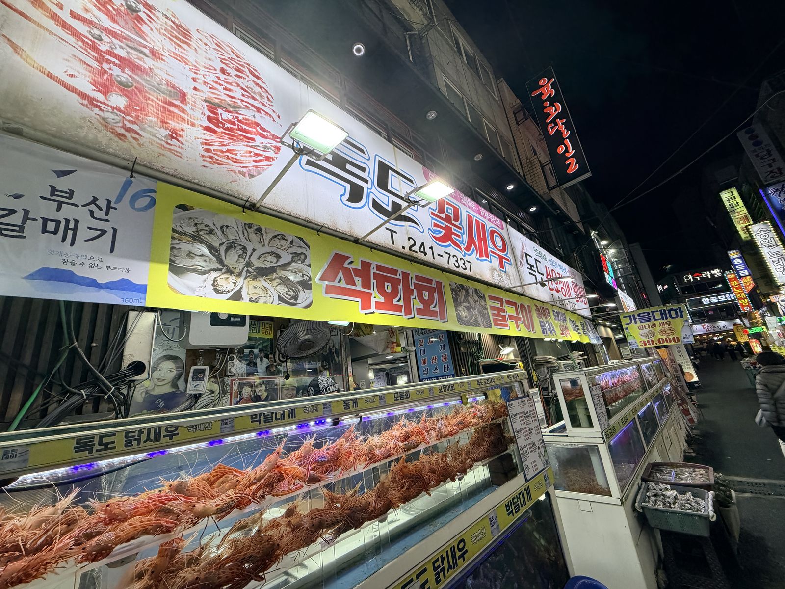 釜山南浦洞活蝦街夜景,店家門口整排藍光活體水族箱與霓虹招牌