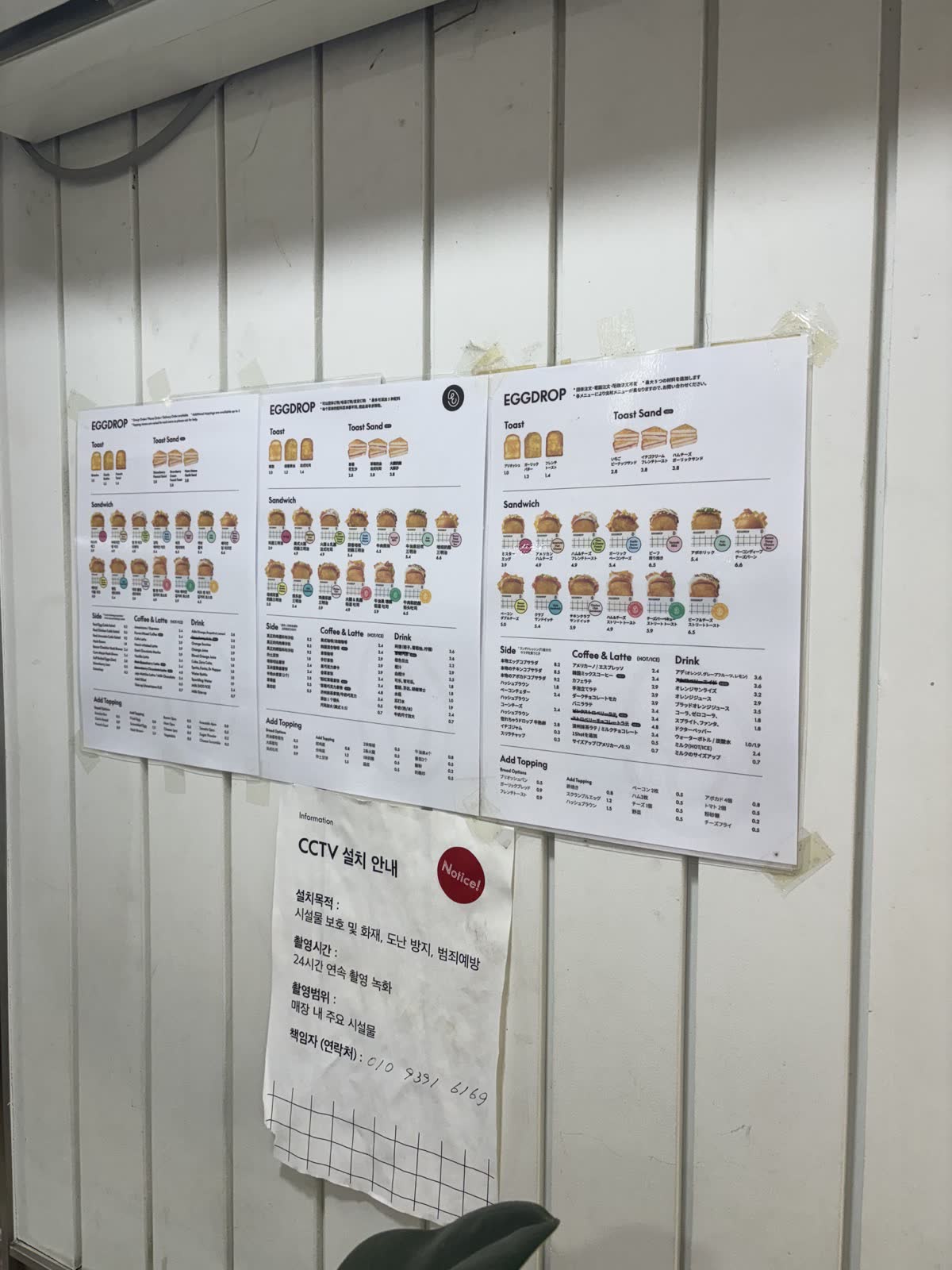 Egg Drop 牆上的中文、英文、日文菜單，列出三明治與飲料價位