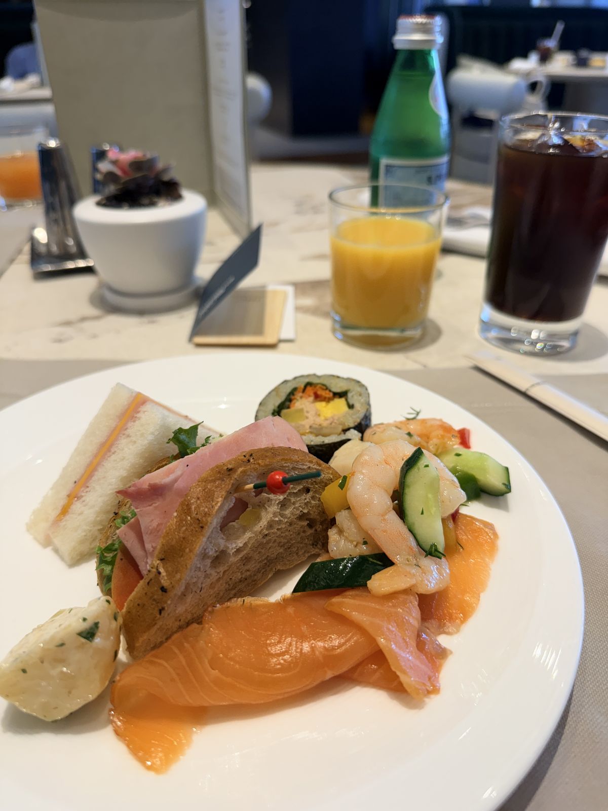 行政酒廊早餐餐盤上的燻鮭魚、蝦、三明治與紫菜飯捲