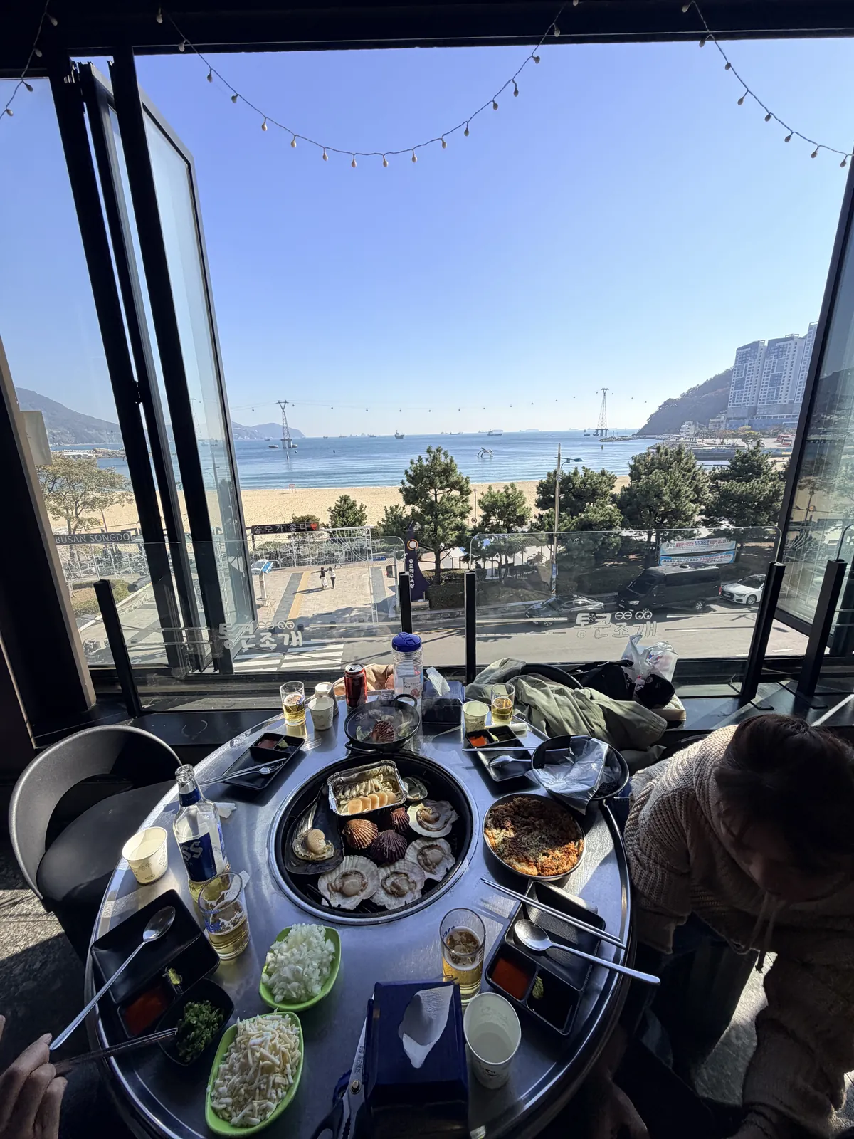 釜山松島 Jogae, Clam 餐桌上的烤蛤蜊與窗外松島海水浴場