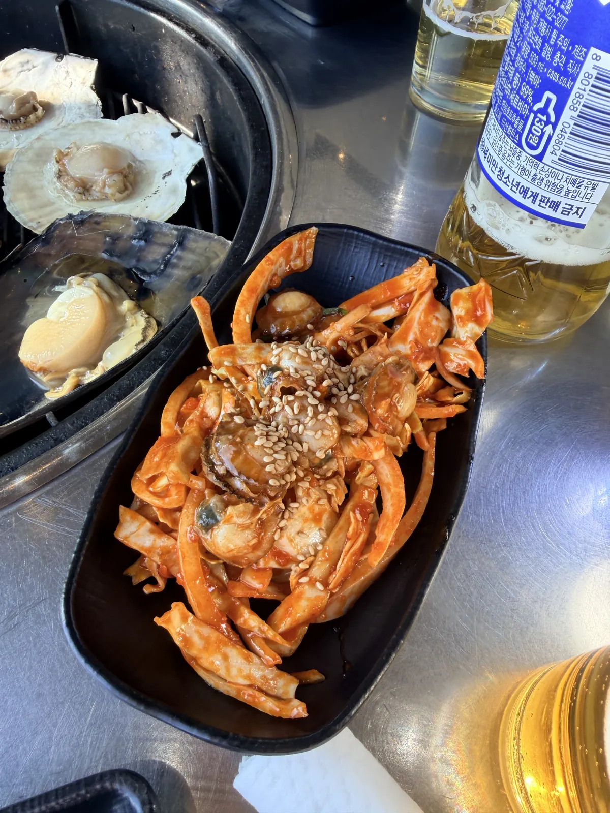 송도통큰조개 造訪當日的辣味拌菜，旁邊是正在烤的扇貝與大型貝類