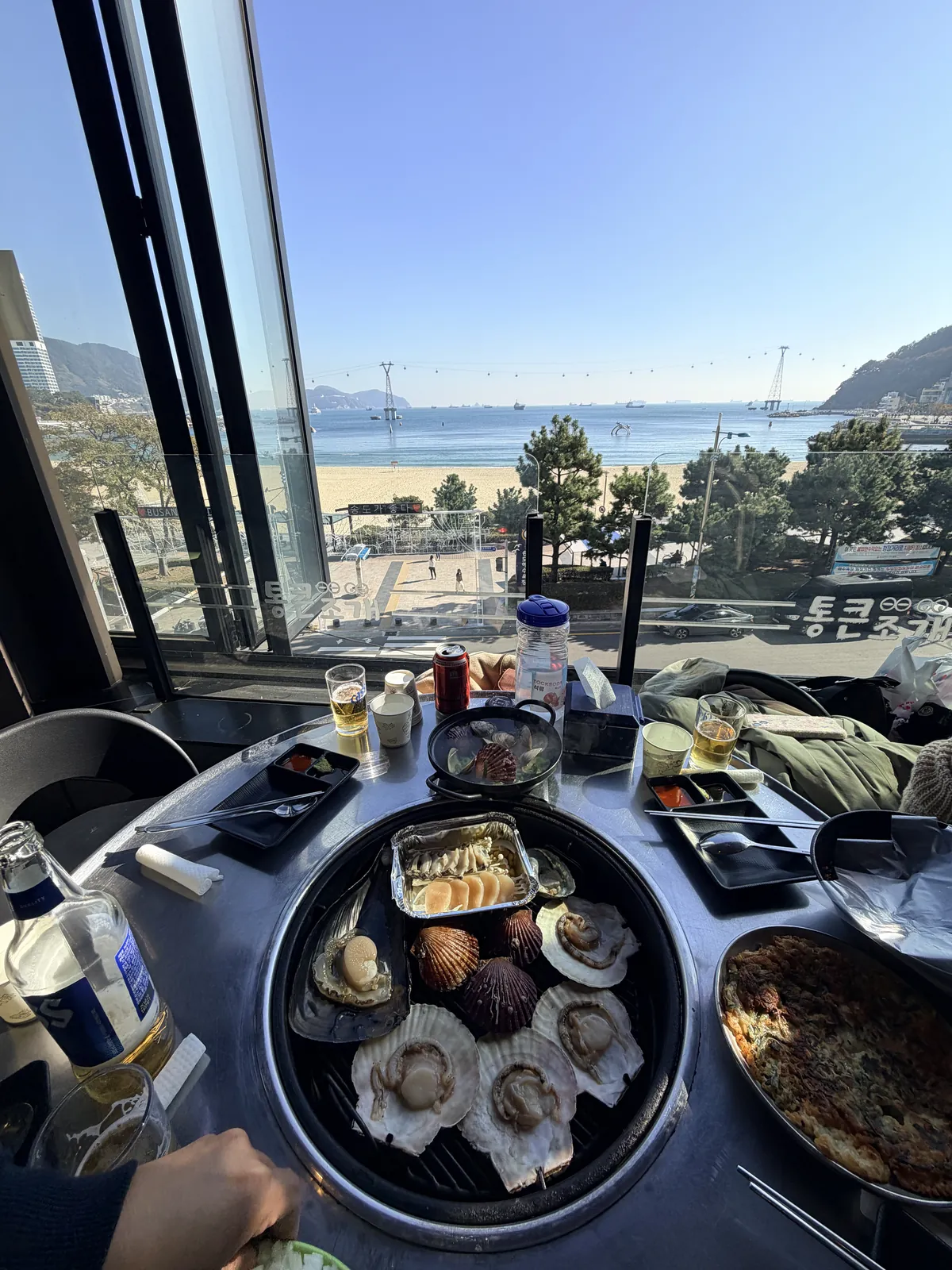 窗邊餐桌上的烤蛤蜊、配菜與松島海水浴場全景