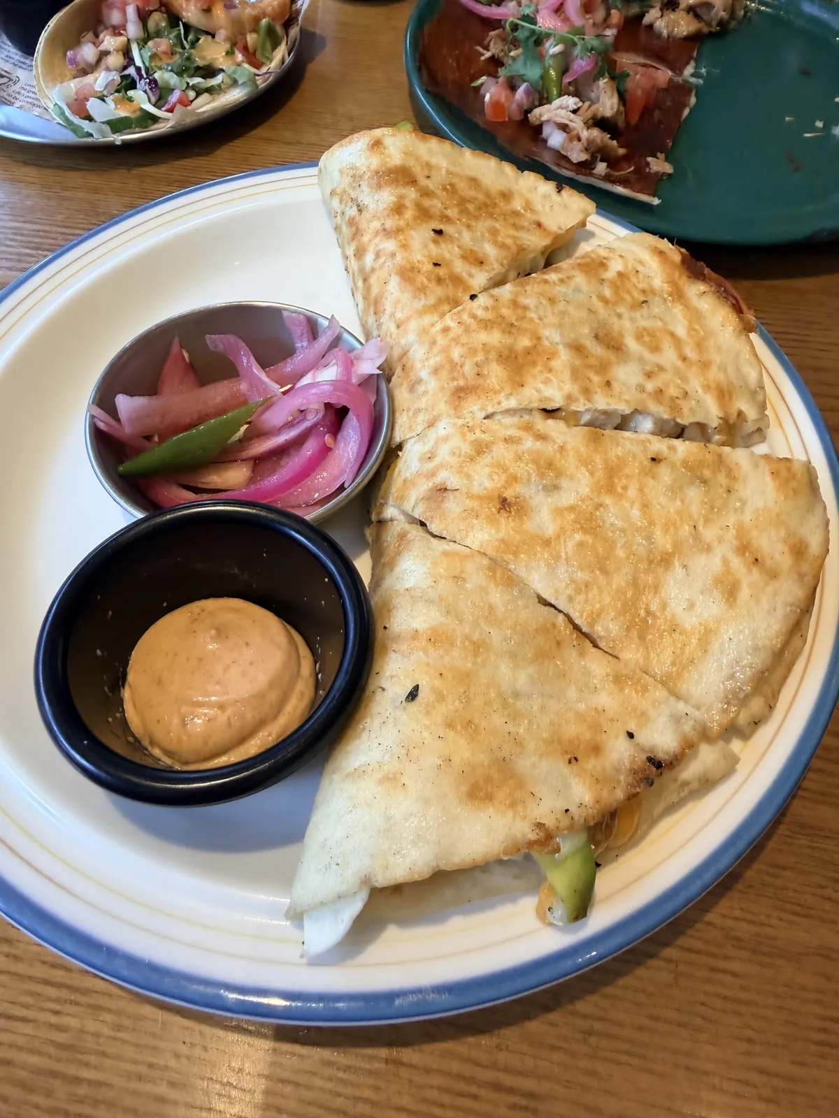 El Carnitas Double Quesadilla 切塊上桌，旁附醃洋蔥、青辣椒與沾醬