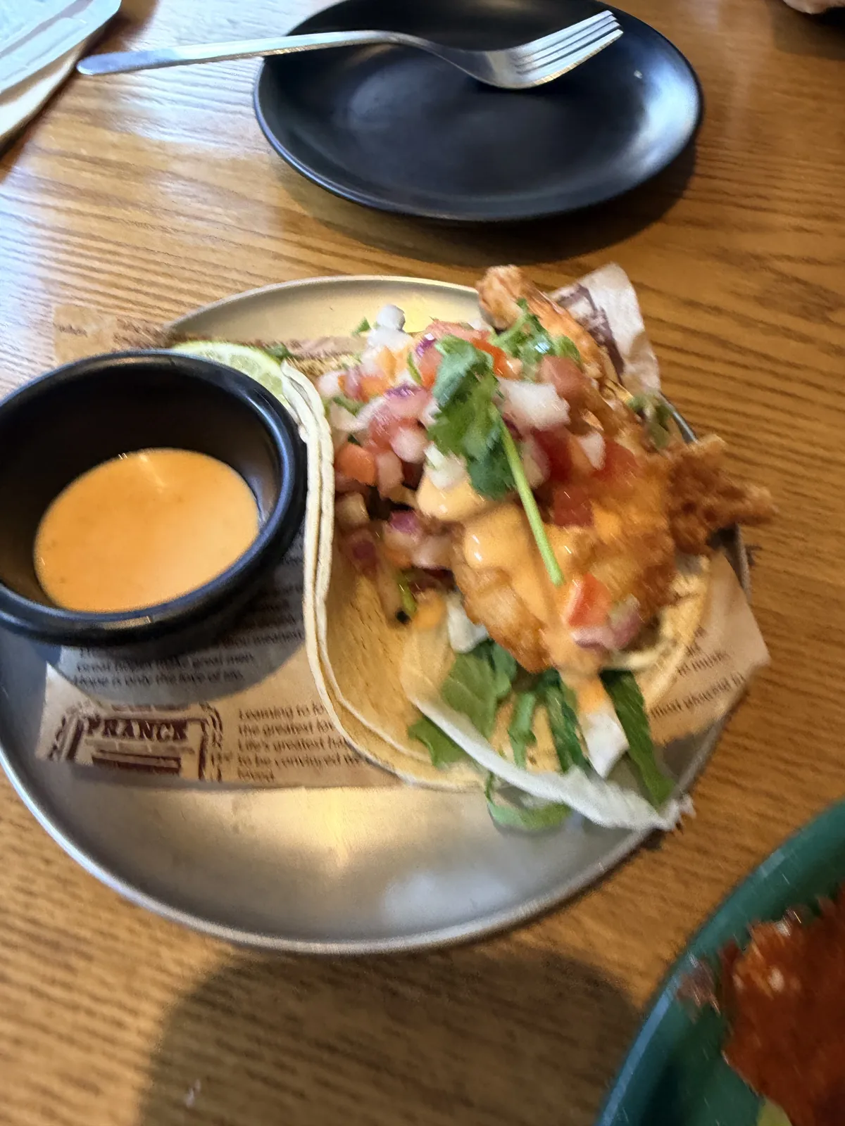 兩份炸蝦 Taco，鋪有生菜、番茄、洋蔥、香菜與橘色醬汁