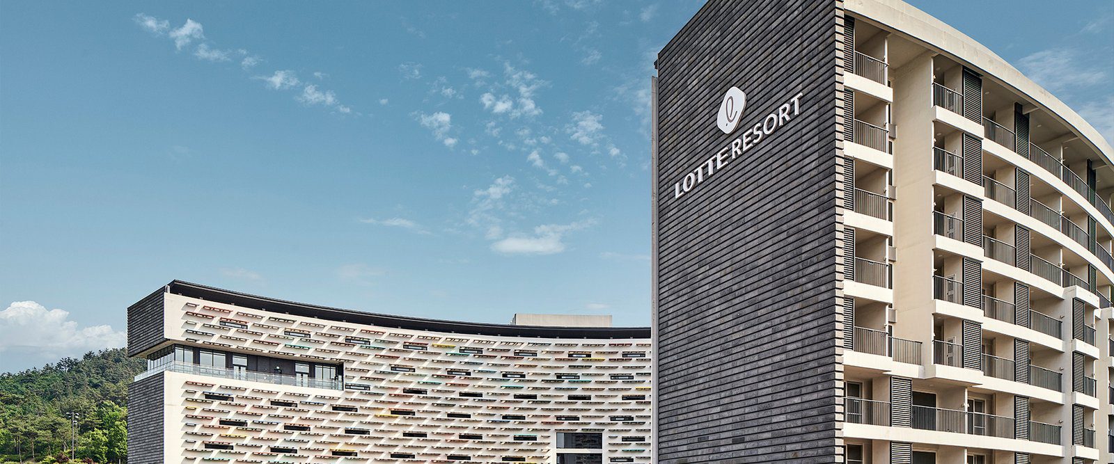 扶餘樂天度假村深灰色塔樓上的 LOTTE RESORT 標誌與彩色弧形外牆