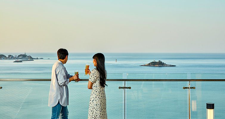 兩位旅客在玻璃護欄露台眺望東海與近岸小島