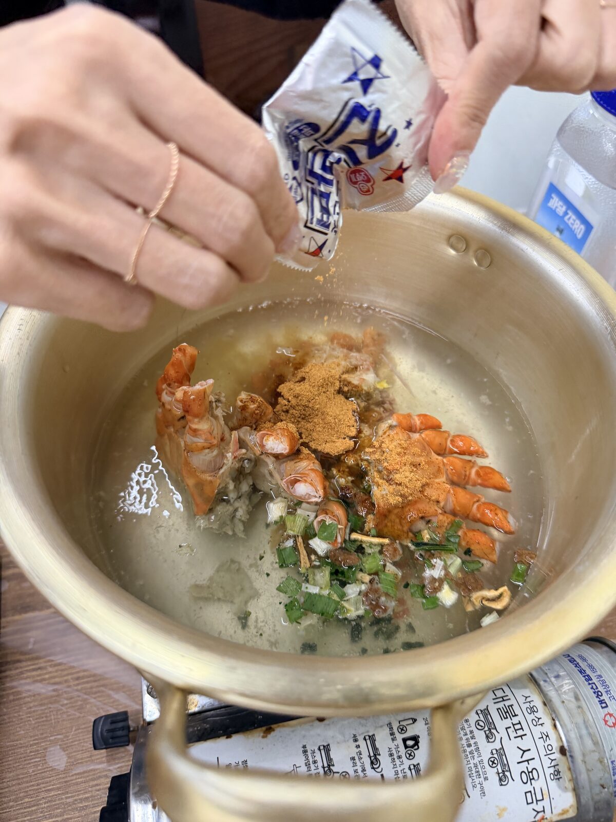 紅蟹拉麵下鍋前,鍋中放入蟹身、蟹腳、蔥與調味粉