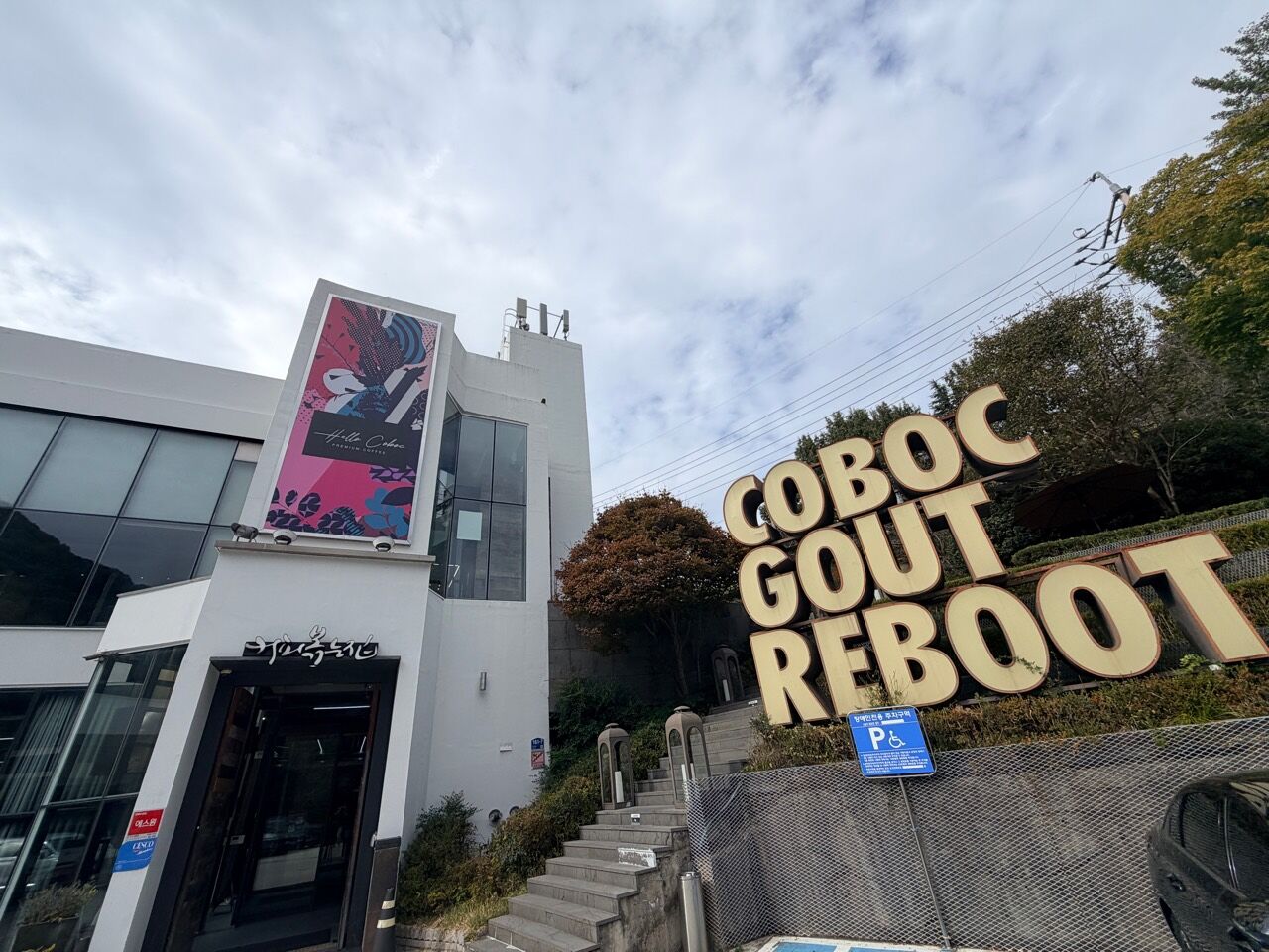 COBOC 白色建築入口與山坡旁的大型字母招牌