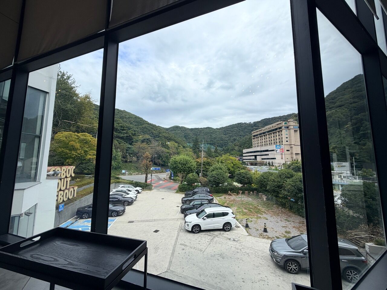 大片玻璃窗外的停車場道路與綠色山坡