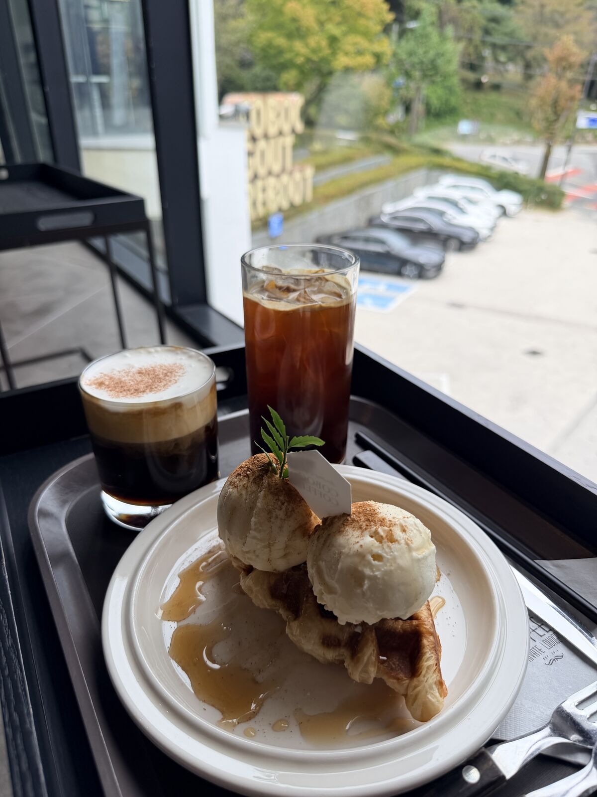窗邊托盤上的兩杯咖啡與雙球冰淇淋鬆餅
