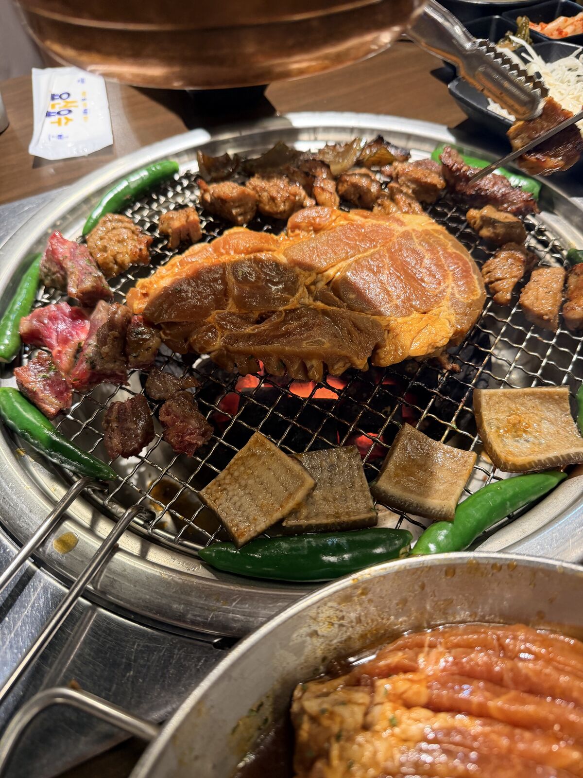 炭火烤網中央的醃肉排與周圍青椒方形豬皮