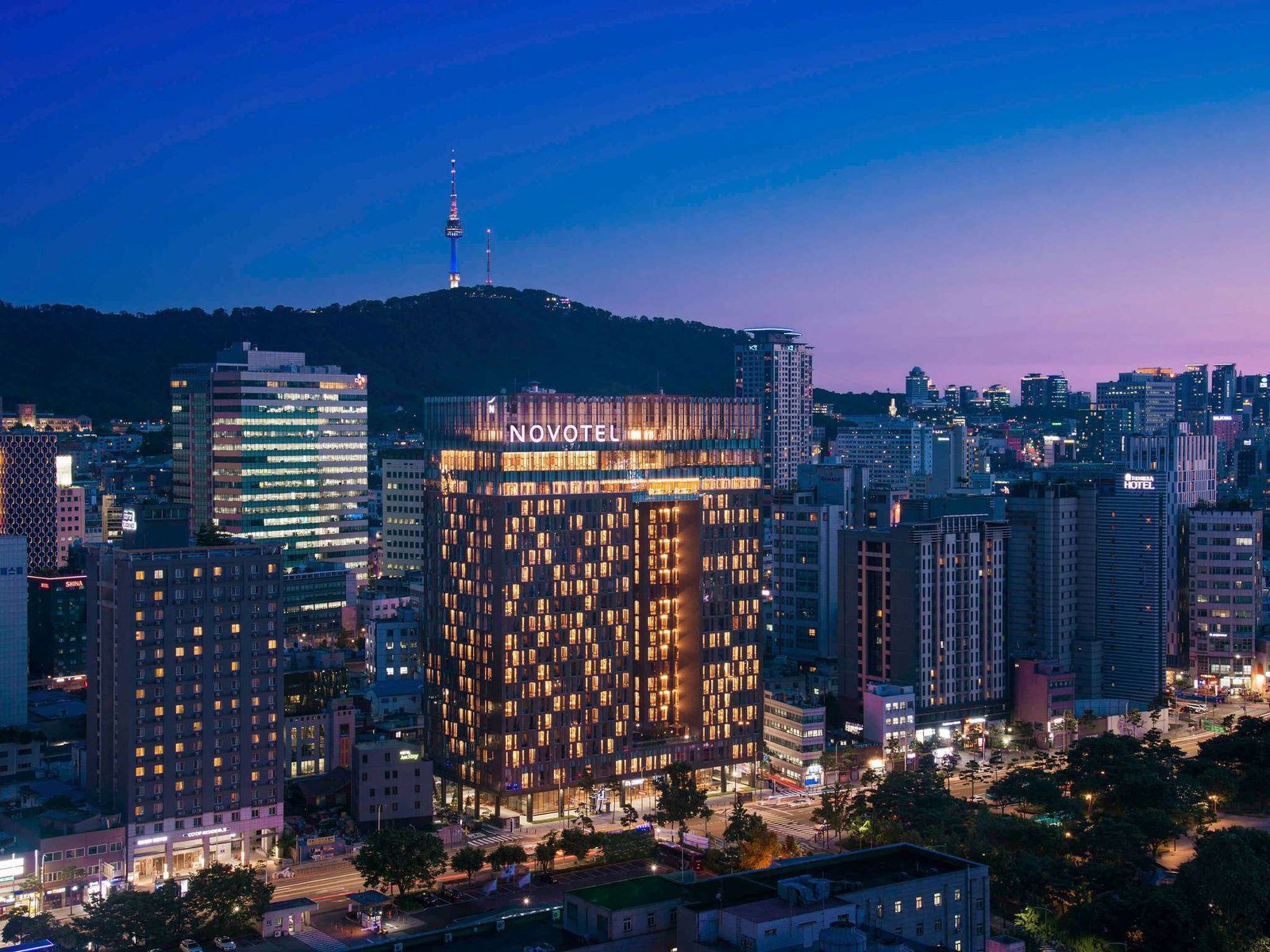 首爾東大門諾富特大使酒店的大樓夜間外觀與後方南山首爾塔