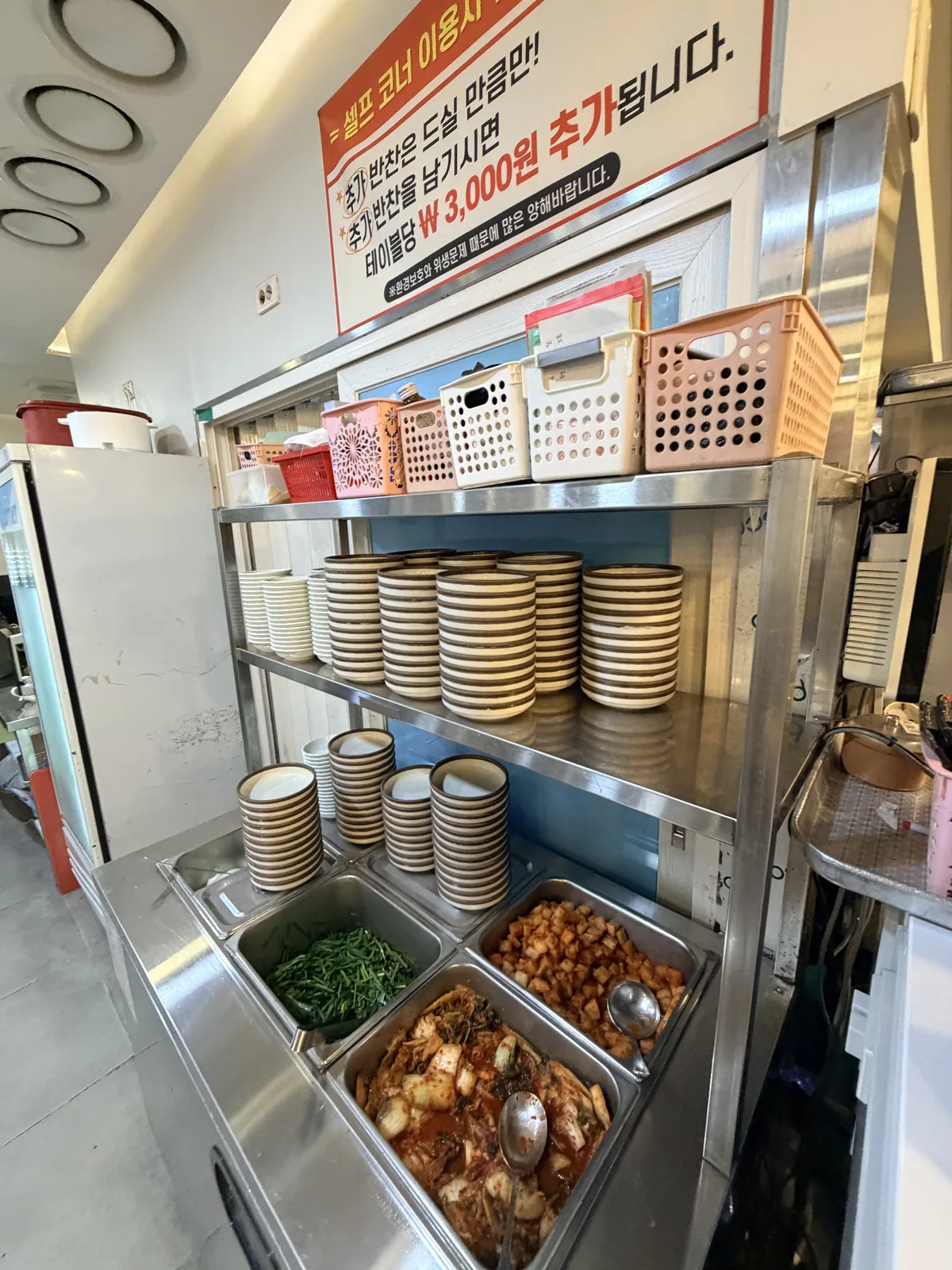 松亭三代國飯自助小菜區，泡菜、蘿蔔塊與辣椒醬，牆上提醒剩菜加收 3,000 韓元