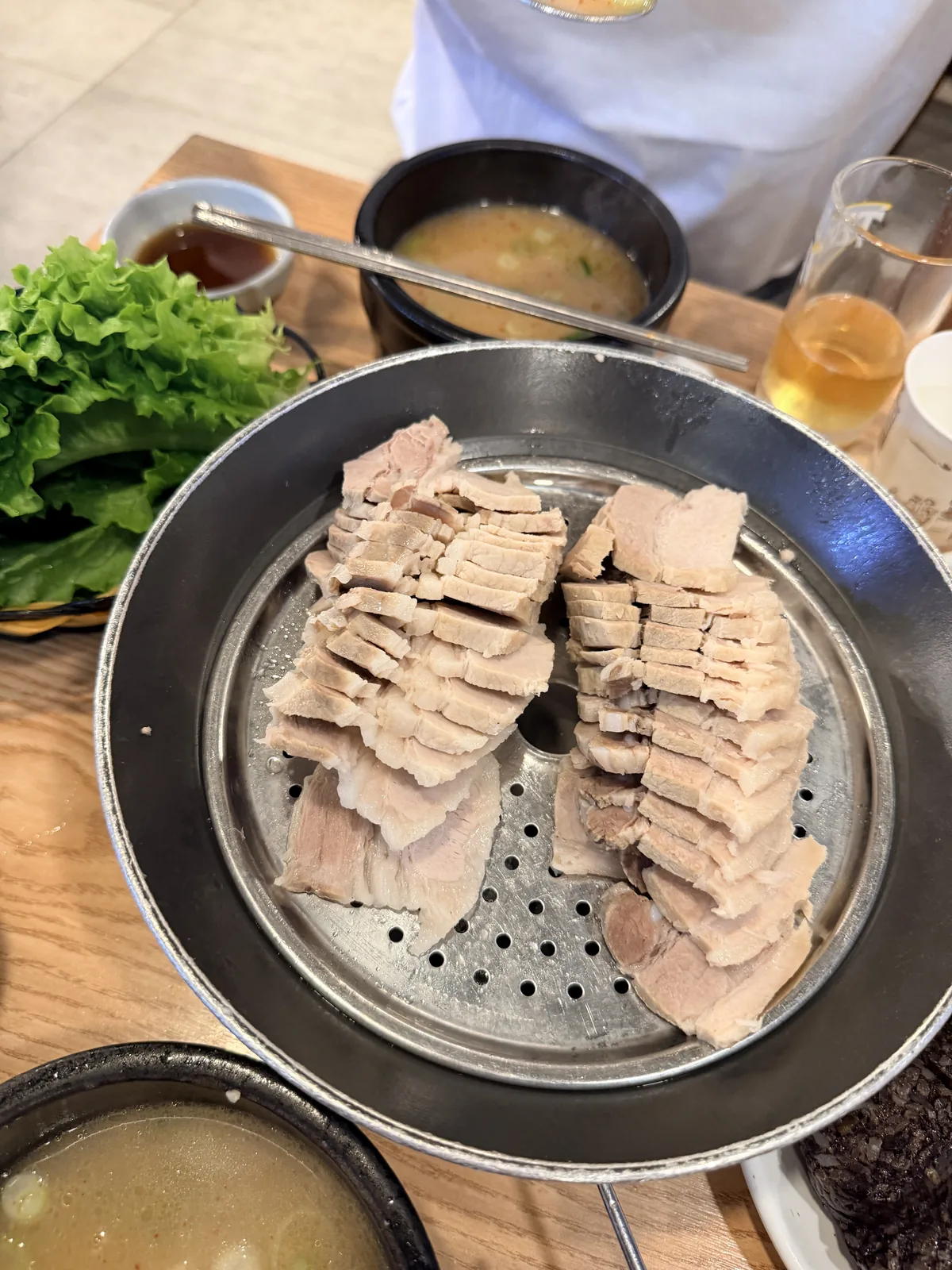 松亭三代國飯白切豬肉放在蒸盤上，旁邊有生菜與湯飯